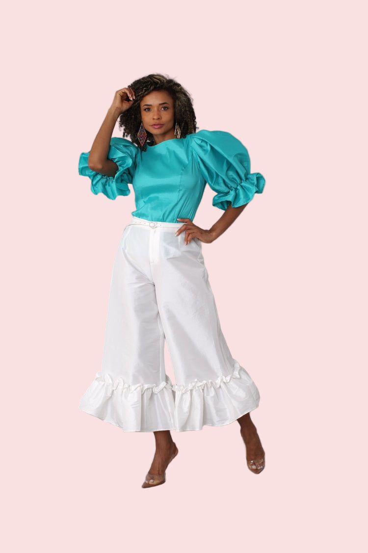 Model wearing off white dramatic ruffle hem wide leg pants standing front-facing with clean elegant silhouette by For Her NYC