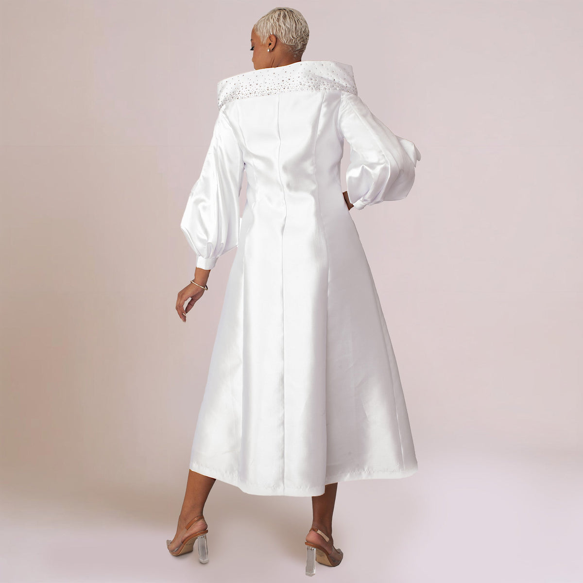White elegant one-piece cassock robe with embellished portrait collar and jeweled buttons, model walking away back view — Tally Taylor