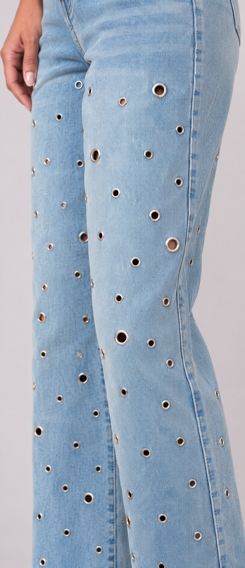 Side close-up of a model wearing the medium wash For Her NYC Grommet Detail Straight Leg Jeans - 82989, highlighting the mixed-size silver grommets