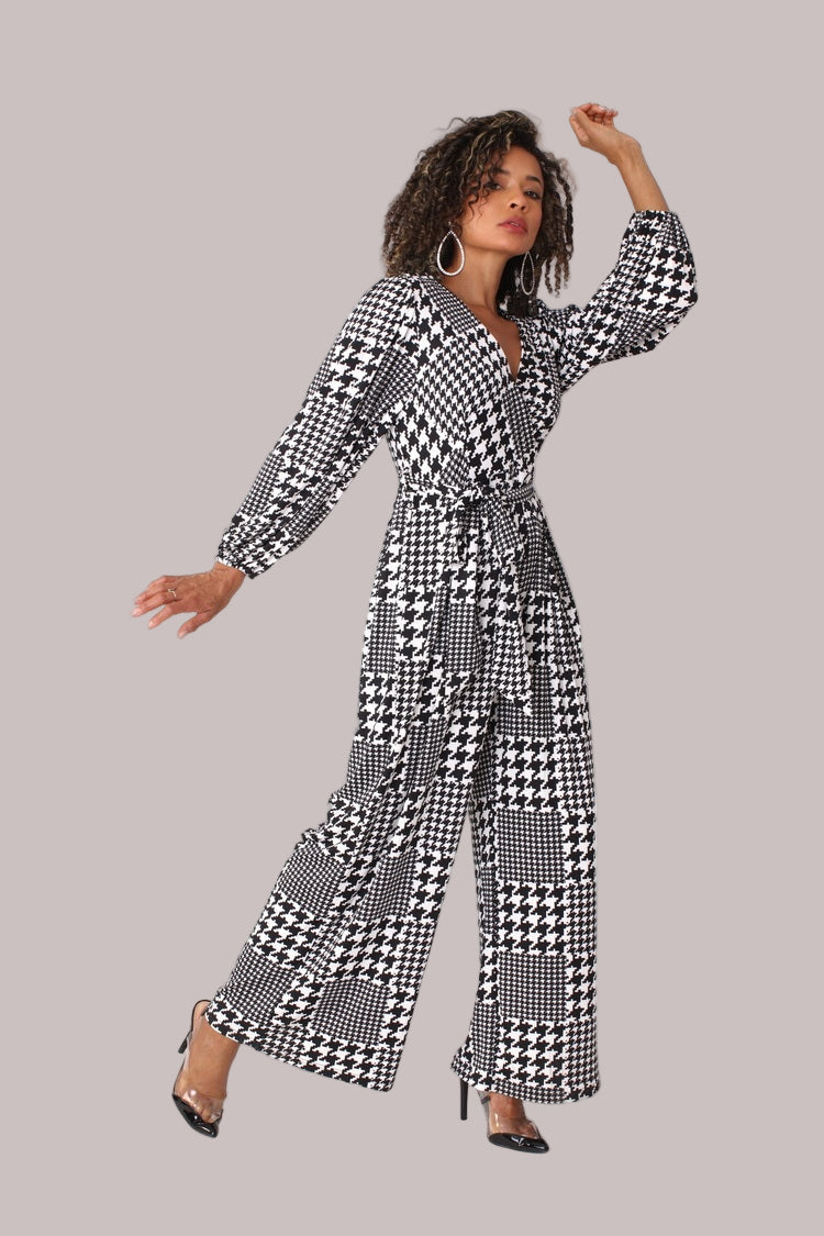 Model posing with arm extended wearing houndstooth wide-leg jumpsuit with puff sleeves by For Her NYC