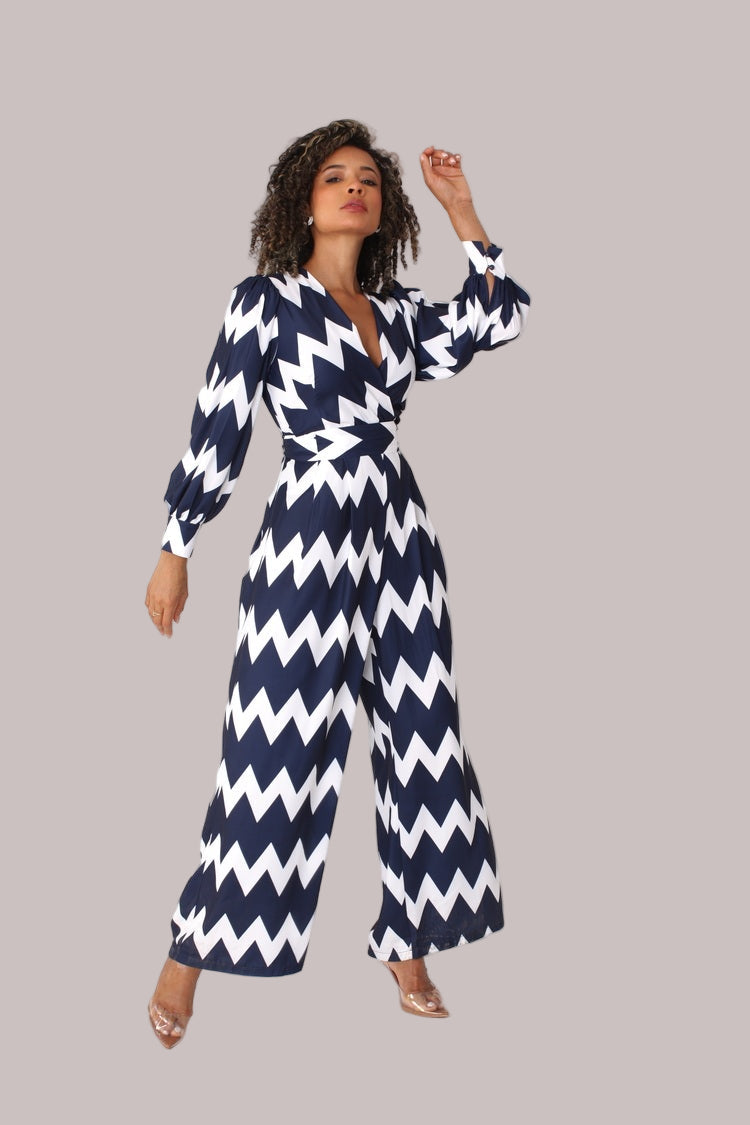 Model posing with arm bent wearing navy and white chevron wide-leg jumpsuit with puff sleeves by For Her NYC