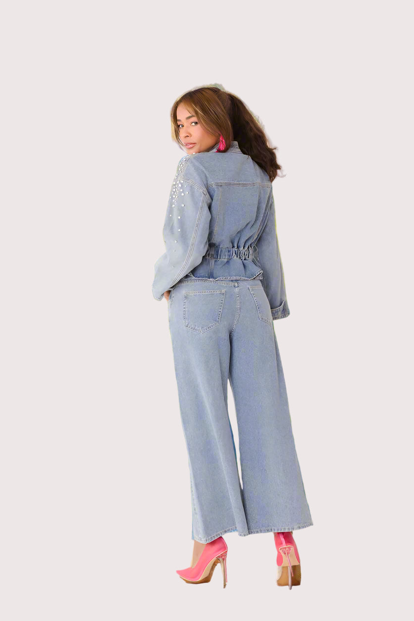 Pearl Cascade peplum denim jacket style 82325 in denim shown from the back in a standing pose emphasizing the gathered waist and flowing peplum design by For Her NYC