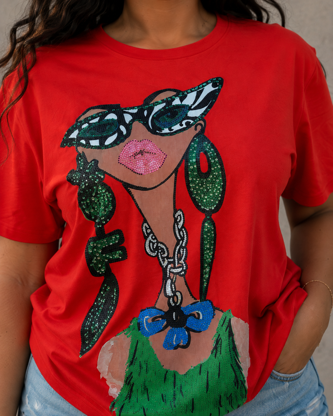 Coral graphic tee featuring a glamorous fashion illustration with glitter embellishments modeled with jean shorts in a studio pose For Her 