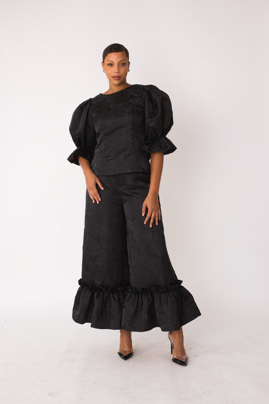 Midnight Drama ruffle set style 82375 in black shown from the front in a standing pose highlighting the jacquard texture, puff sleeves, and ruffle hem by For Her NYC