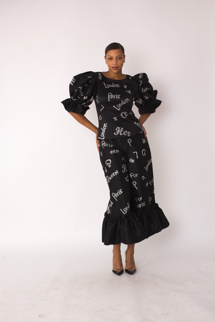 City Lights ruffle set style 82383 in black and silver shown from the back in a standing pose highlighting the silhouette, ruffle hem, and allover city text print by For Her NYC