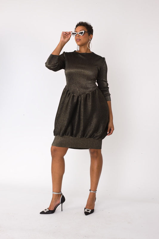 Metallic bubble hem sweater dress in black gold shown in front pose with hand raised to face by For Her NYC