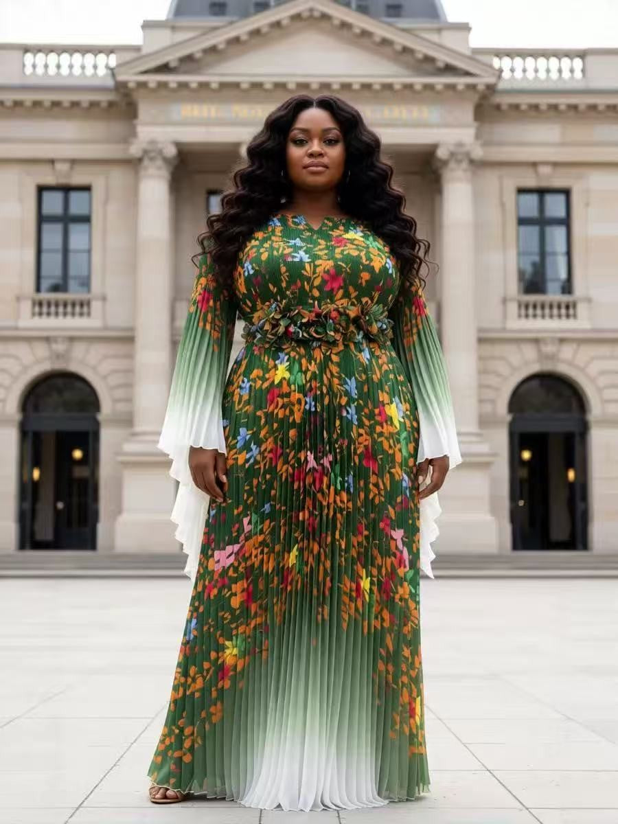 Emerald green floral pleated maxi dress with sheer long sleeves and statement waist detail modeled in a front-facing pose outdoors For Her NYC Emerald Green