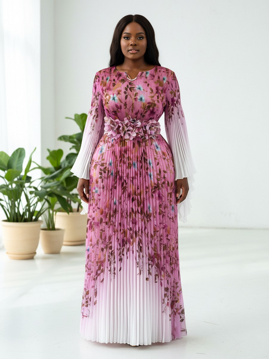 Pink multi floral pleated maxi dress with statement waist detail and sheer long sleeves modeled in a front-facing pose against a bright studio background For Her NYC Pink Multi