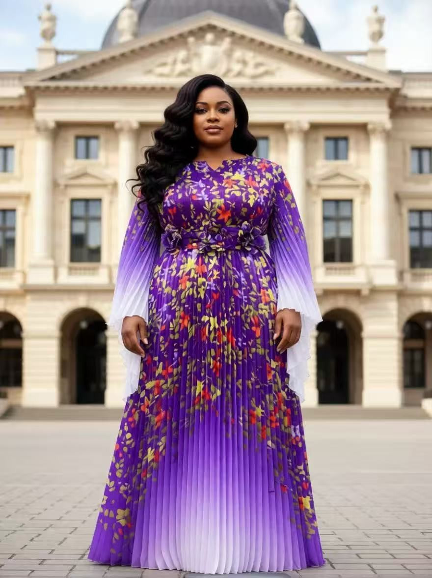 Purple floral pleated maxi dress with statement waist detail and sheer sleeves modeled outdoors in front of elegant city architecture For Her NYC Purple
