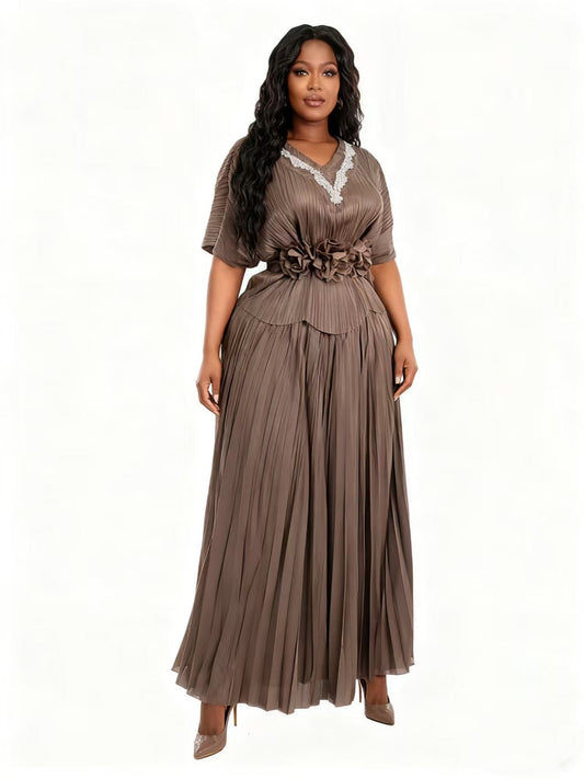 Model wearing a brown pleated floral waist midi dress with flowing skirt and floral waist detail, front pose, For Her NYC