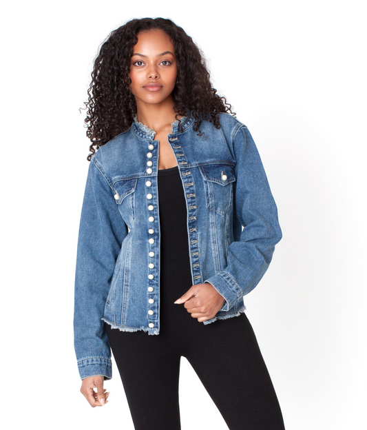 Pearl button denim jacket with structured fit and subtle frayed hem, model standing with hand on hip layered over black top For Her NYC