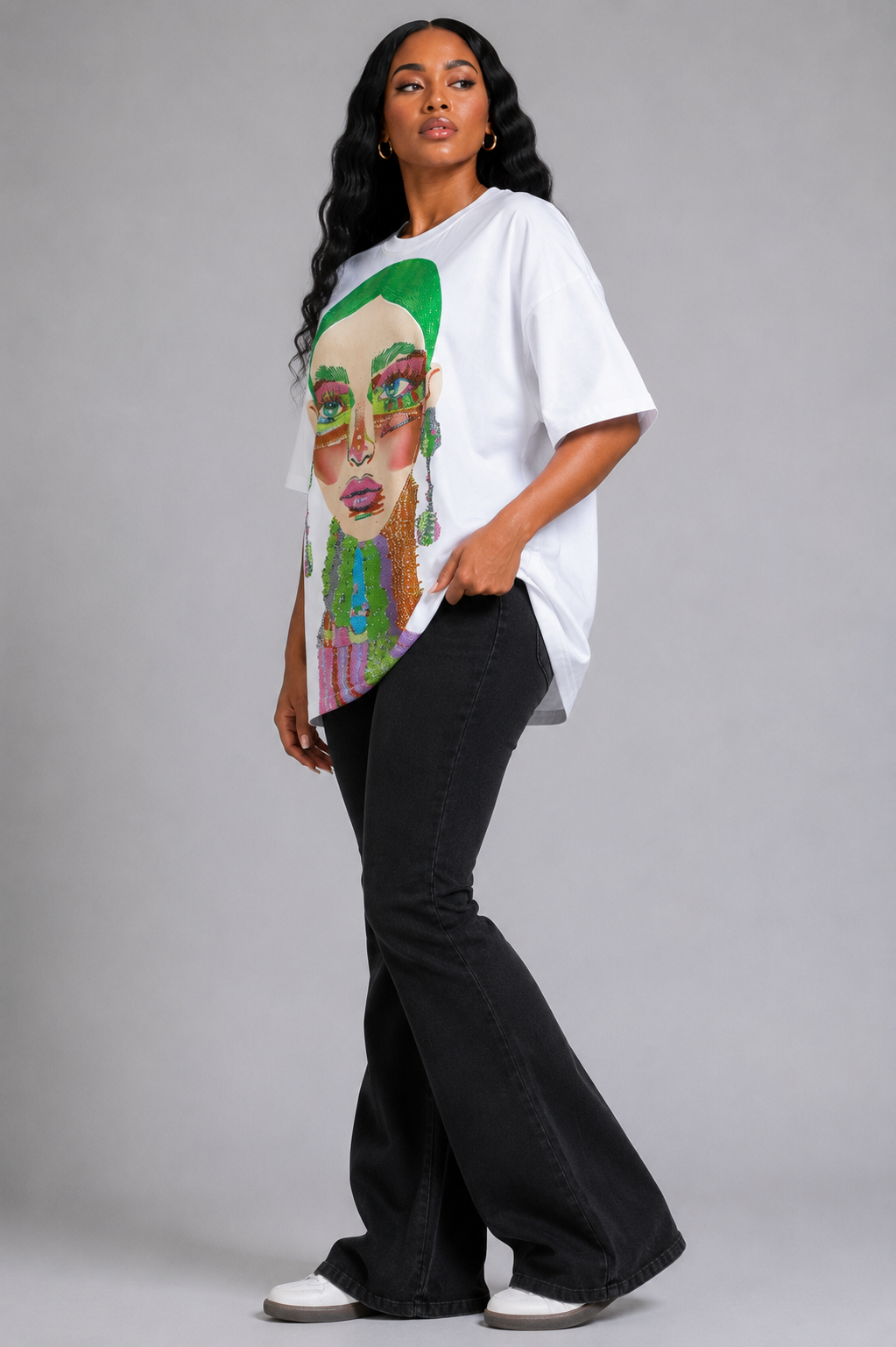 White/Multi graphic tee featuring vibrant electric portrait artwork with rhinestone detailing, model standing front view wearing tall boots For Her NYC