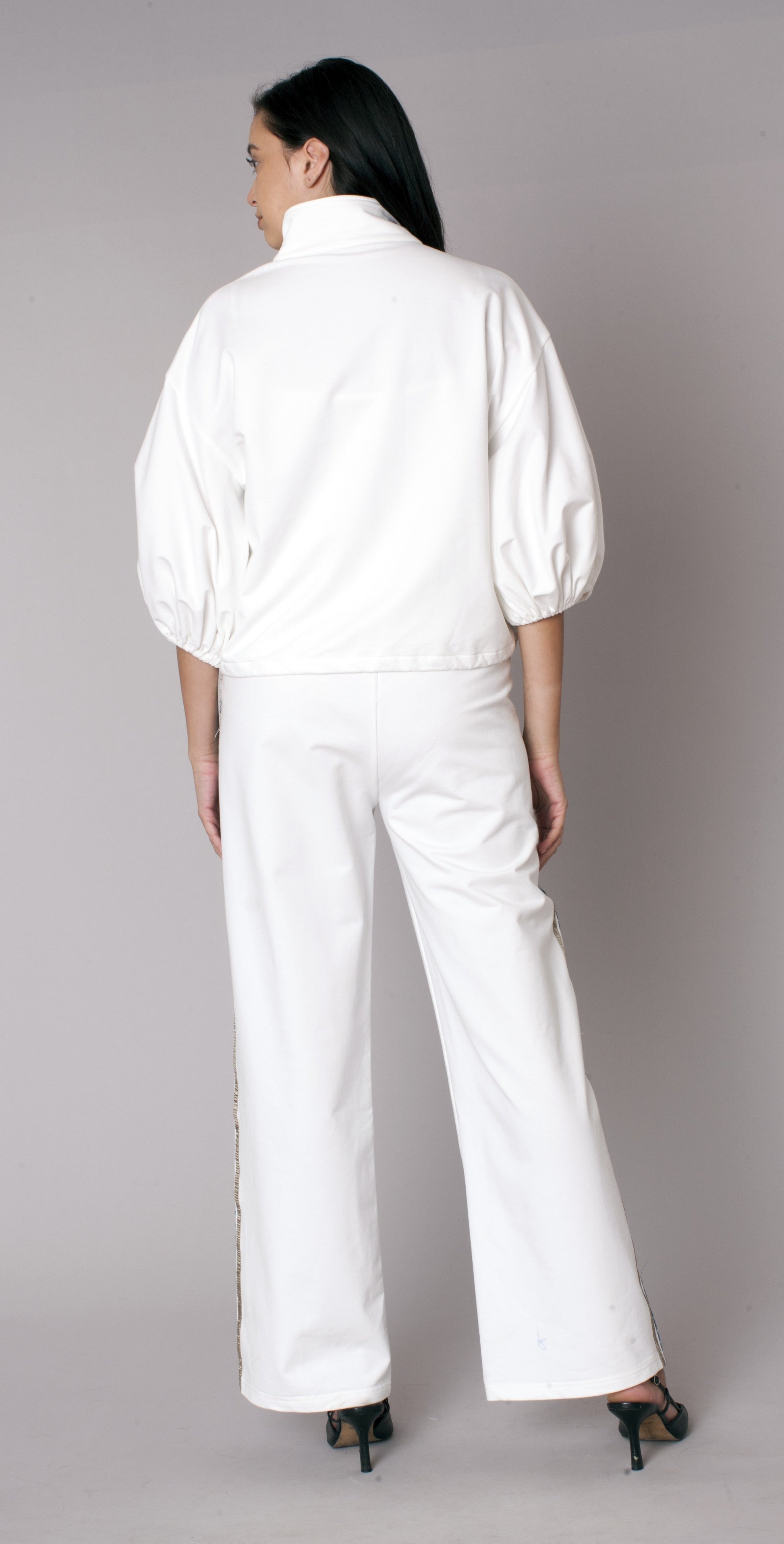 Back view of a white athleisure track pant set featuring a relaxed zip-front jacket and wide leg pants with polished detailing – For Her NYC