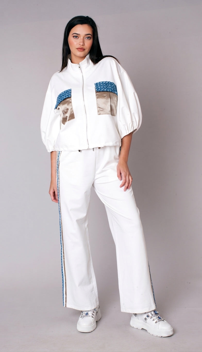 Woman wearing a white embellished track pant set with zip-front jacket, puff sleeves, satin pocket accents, and wide leg pants – For Her NYC