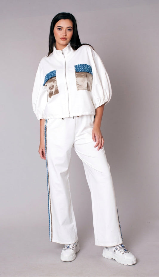 Woman wearing a white embellished track pant set with zip-front jacket, puff sleeves, satin pocket accents, and wide leg pants – For Her NYC