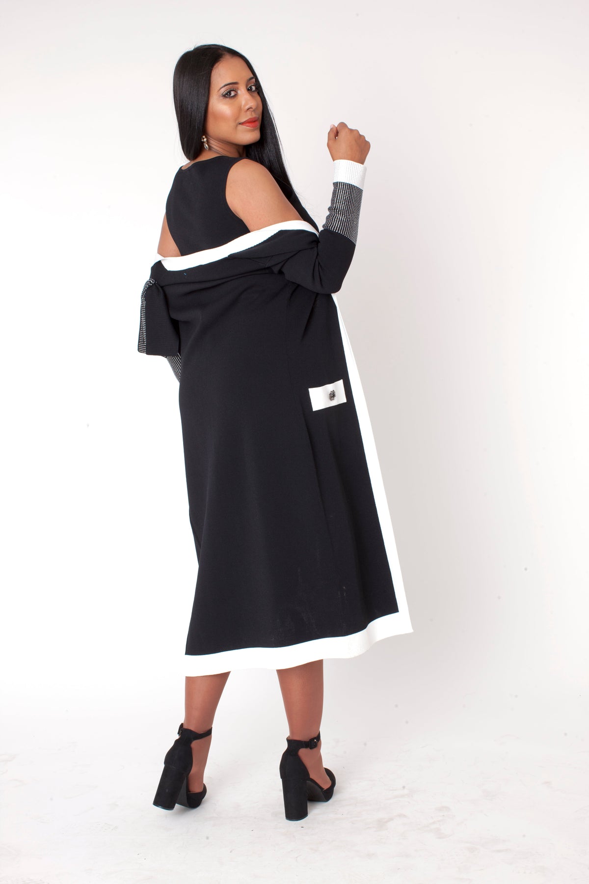 Three quarter angled view of model wearing the black and white Camille trim knit jacket dress plus size, emphasizing elegant movement and contrast trim design by Tally Taylor