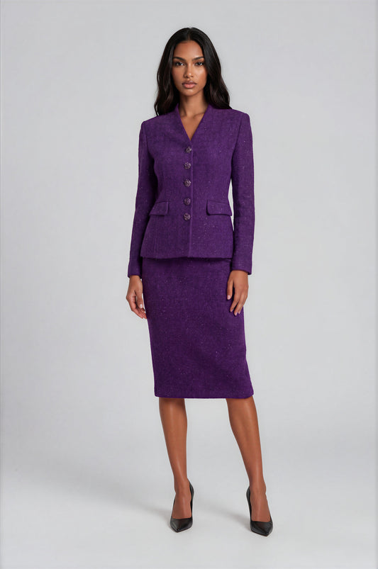 Woman wearing a deep purple two-piece skirt suit featuring a tailored blazer with decorative crystal trim and a coordinating knee-length pencil skirt. Tally Taylor.
