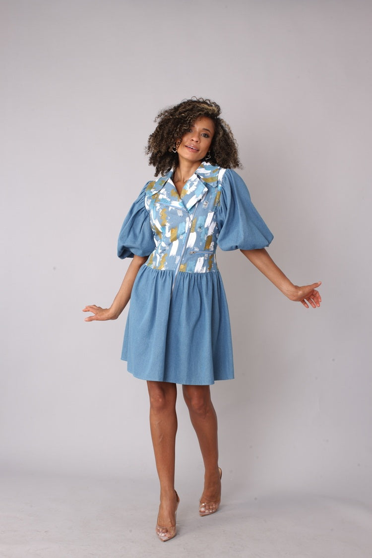 Denim blue puff sleeve dress shown in a front walking pose, featuring an abstract print bodice, zip-up front, and flared skirt, playful statement dress by For Her NYC