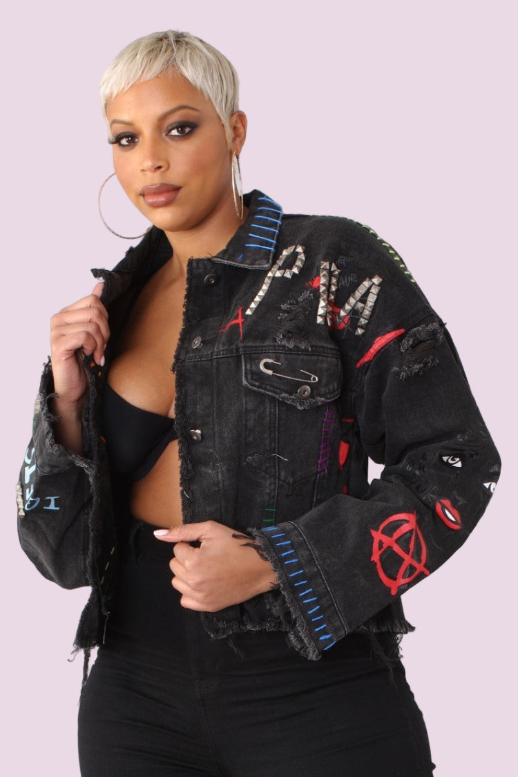 Black distressed denim jacket with colorful embroidery front view styled with cropped silhouette for edgy streetwear look.