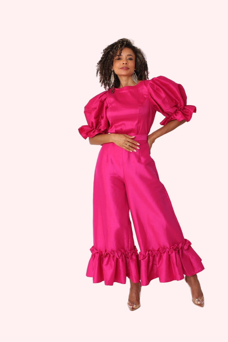 Model wearing fuchsia dramatic ruffle hem wide leg pants standing front-facing with bold statement color by For Her NYC