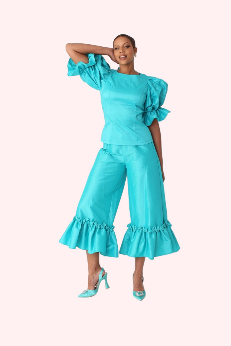 Model walking forward in jade dramatic ruffle hem wide leg pants highlighting movement and flow by For Her NYC