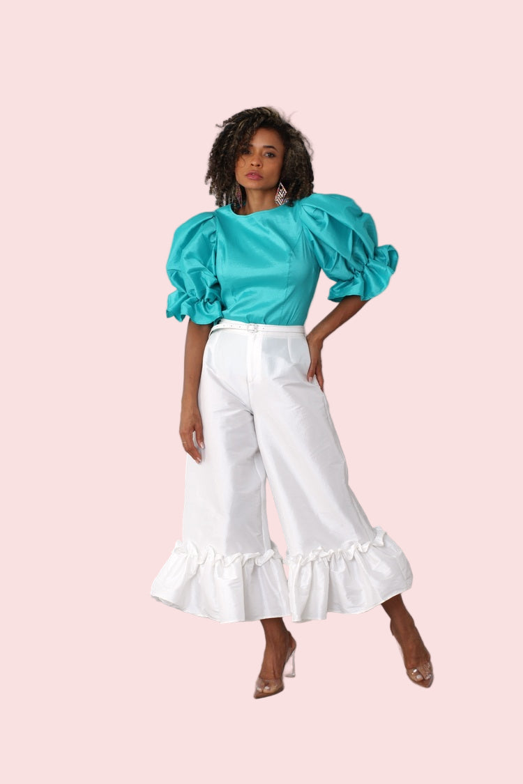 Model posing with arm raised in off white dramatic ruffle hem wide leg pants showcasing statement hem detail by For Her NYC