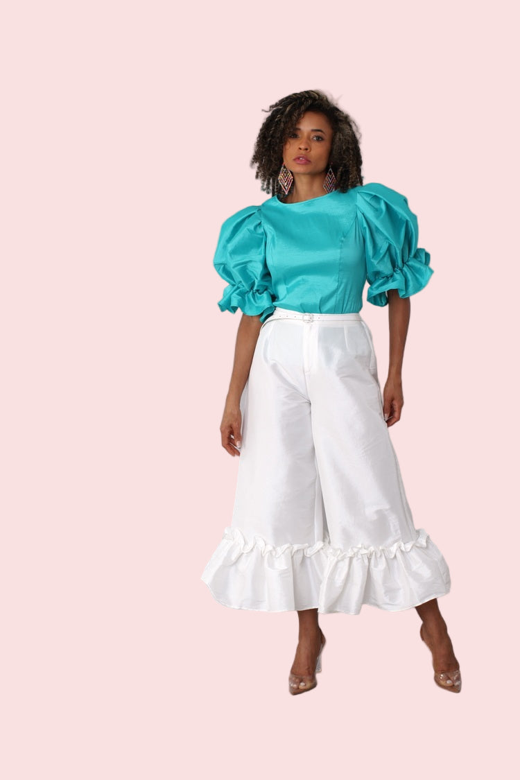 Model wearing off white dramatic ruffle hem wide leg pants standing front-facing with clean elegant silhouette by For Her NYC