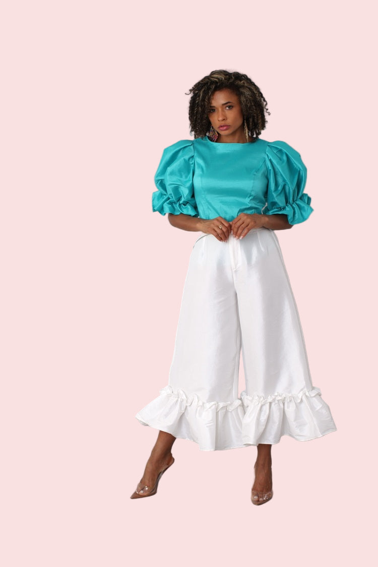 Model walking forward in off white dramatic ruffle hem wide leg pants highlighting wide leg movement by For Her NYC