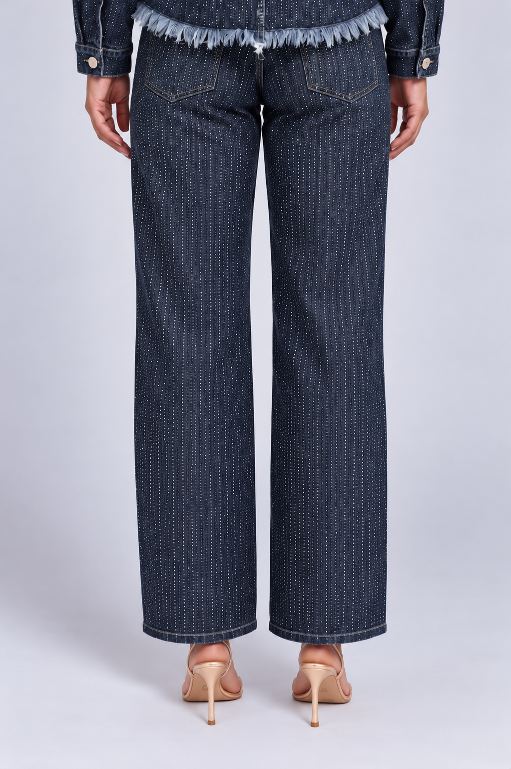 Close back view of a model wearing the For Her NYC Glitter-Effect Flared Denim Pants - 82955 with vertical glitter detailing and back pockets