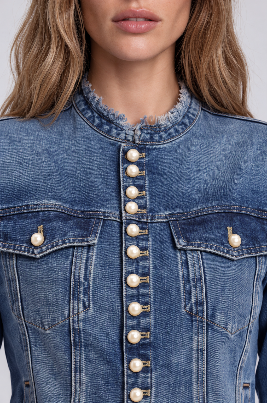 Close-up of a model wearing the For Her NYC Pearl Button Denim Jacket - 83040, highlighting the pearl buttons, chest pockets, and frayed neckline