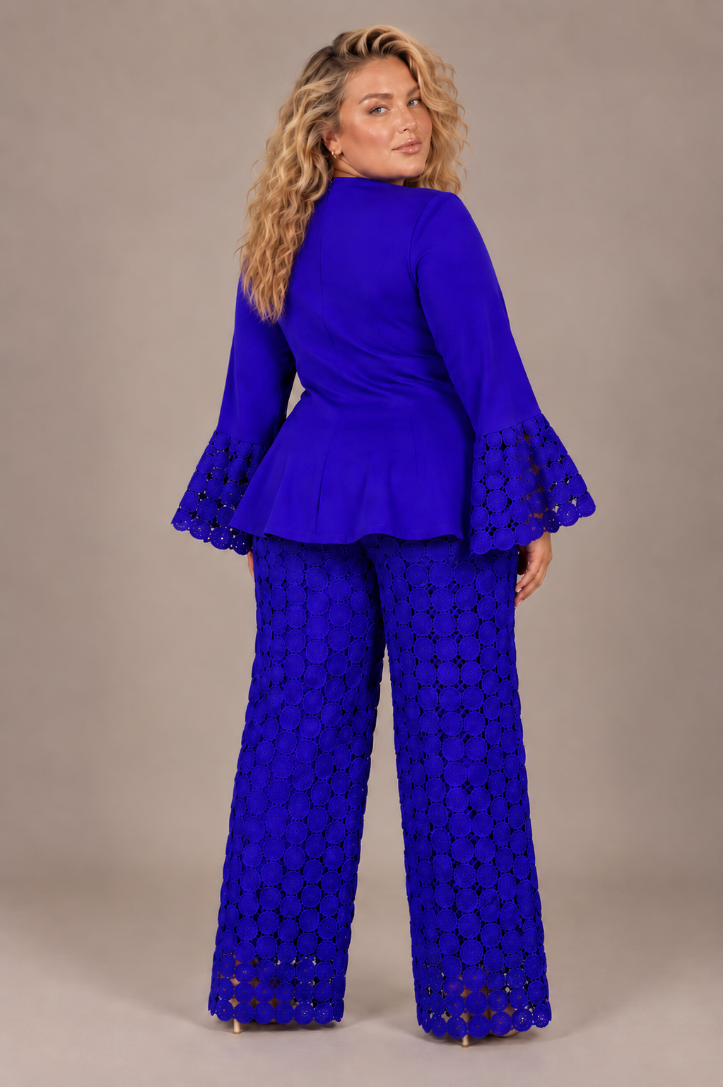 Back view of a plus-size model wearing the royal blue For Her NYC Plus Size New Dimension Peplum Pant Set - U0561W with circular cutout detailing, flared cuffs, and wide-leg pants