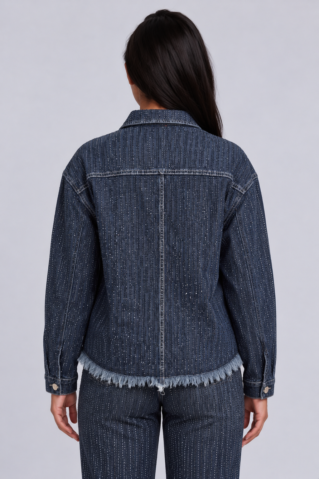 Close back view of a model wearing the For Her NYC Rhinestone Embellished Denim Jacket - 82978, highlighting the dense rhinestone rows and frayed hem