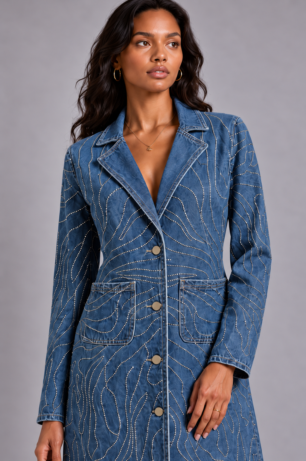 Front detail of a model wearing the medium-wash For Her NYC Rhinestone Swirl Denim Duster Coat - 83070, highlighting the buttons, pockets and rhinestone design