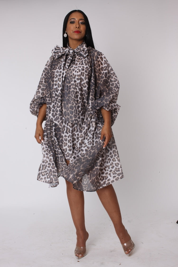 Leopard print organza bow dress walking forward showcasing flowy silhouette and statement bow detail.