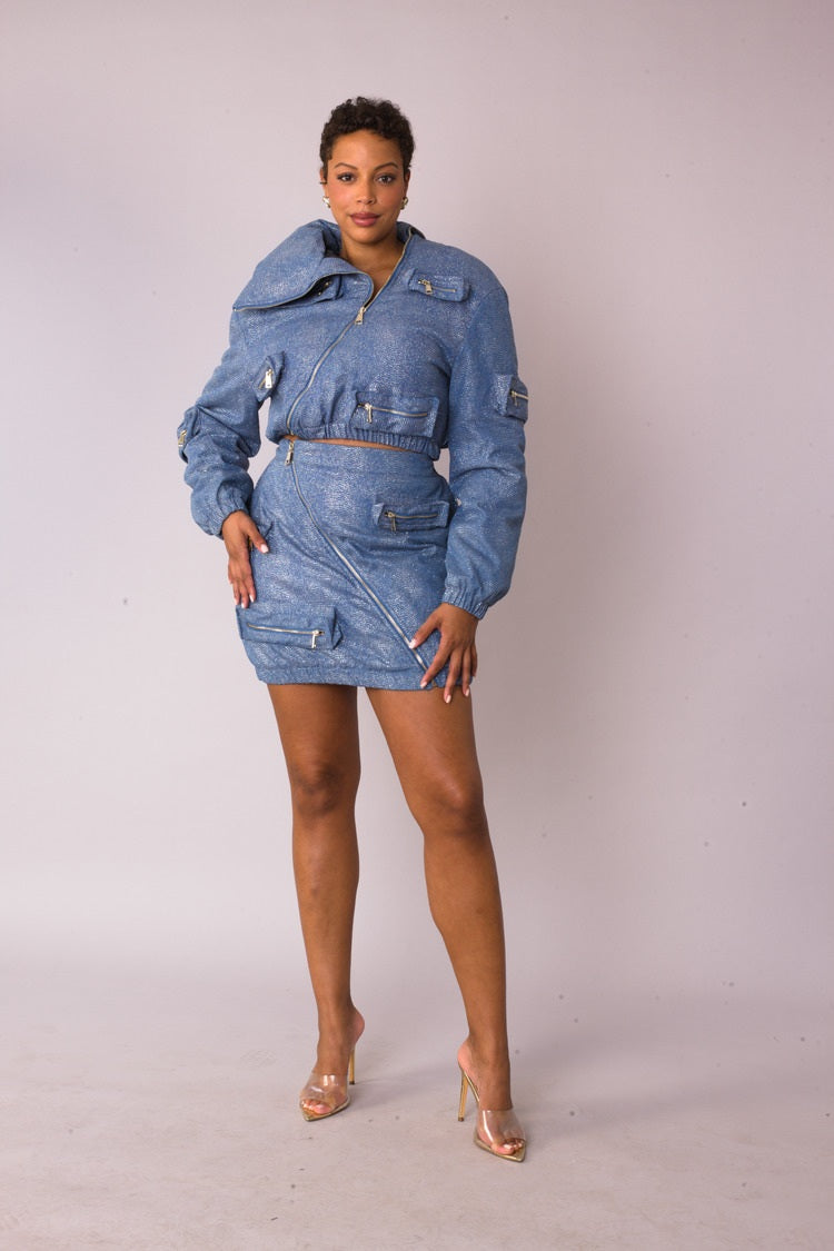 Model wearing the denim silver metallic shimmer mini skirt standing front facing, featuring asymmetrical zip detail and functional pockets by For Her NYC