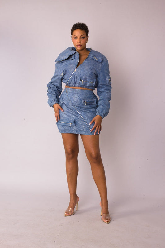 Model wearing the denim silver metallic shimmer mini skirt standing front facing, featuring asymmetrical zip detail and functional pockets by For Her NYC