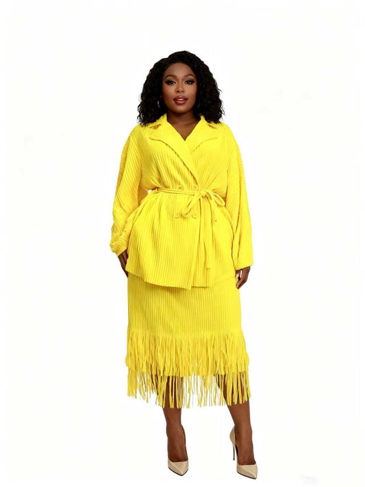 Front view of model wearing a bright yellow pleated skirt suit with wrap-style jacket and fringe hem midi skirt, For Her NYC