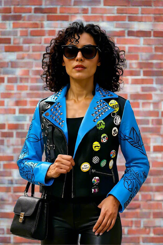 Model wearing  BLUE /BLACK faux leather jacket with pins and studs, front-facing hero pose highlighting moto zipper, studded collar, and floral sleeves by For Her NYC
