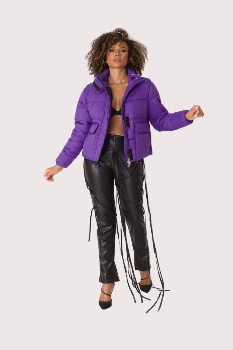Model wearing purple plush puffer jacket, front-facing hero pose highlighting bold color, faux fur texture, and oversized silhouette by For Her NYC