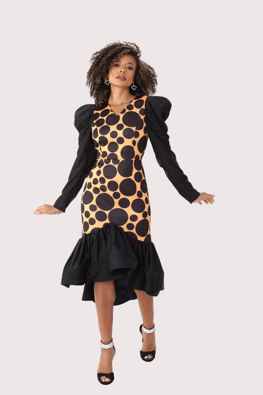 Black and mustard polka dot high-low dress with puff sleeves shown in a front walking pose, featuring a fitted bodice and ruffled hem movement, statement occasion dress by For Her NYC