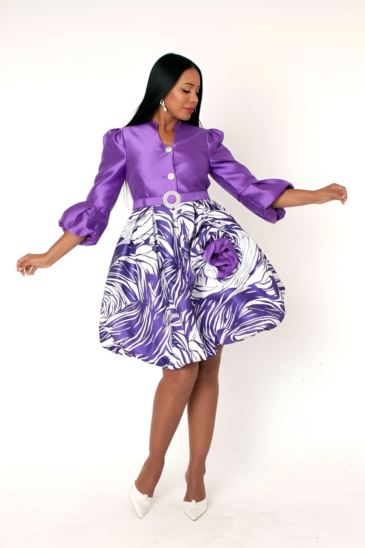 Purple multi puff sleeve fit and flare occasion dress with printed skirt and rosette detail, model twirl pose holding skirt – Tally Taylor
