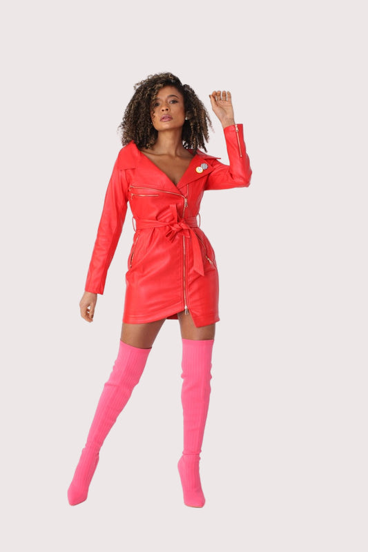 Model wearing red sleek leather zip-up dress with adjustable belt and V-neck front view, styled with pink knee-high boots, For Her NYC