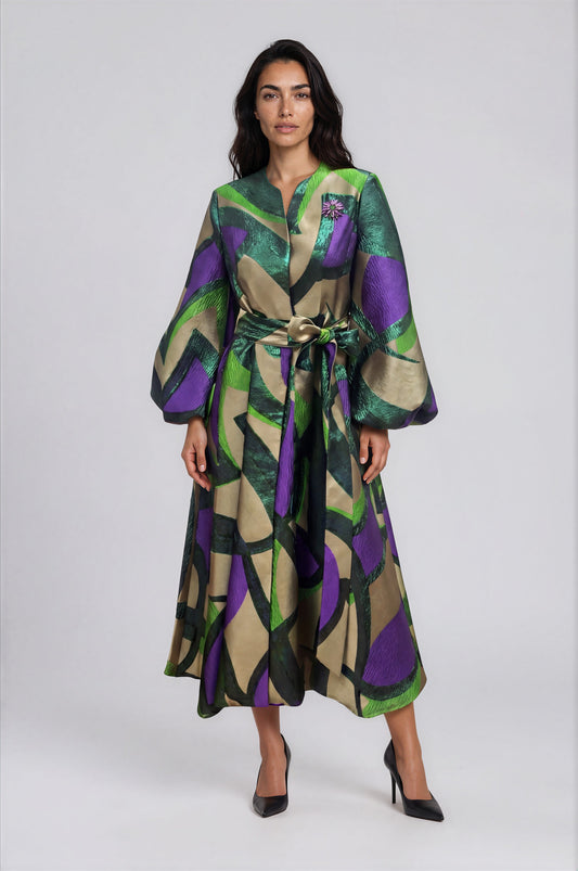 Model wearing the Spring Blossom A-Line Dress in Green Multi featuring a vibrant floral print, belted waist, flowing long sleeves, and a flattering midi-length silhouette by Tally Taylor.