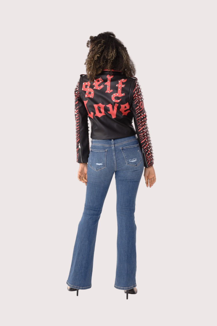 Back view of model wearing a black and red studded leather jacket with detachable sleeves, featuring graphic back design and stud accents, For Her NYC