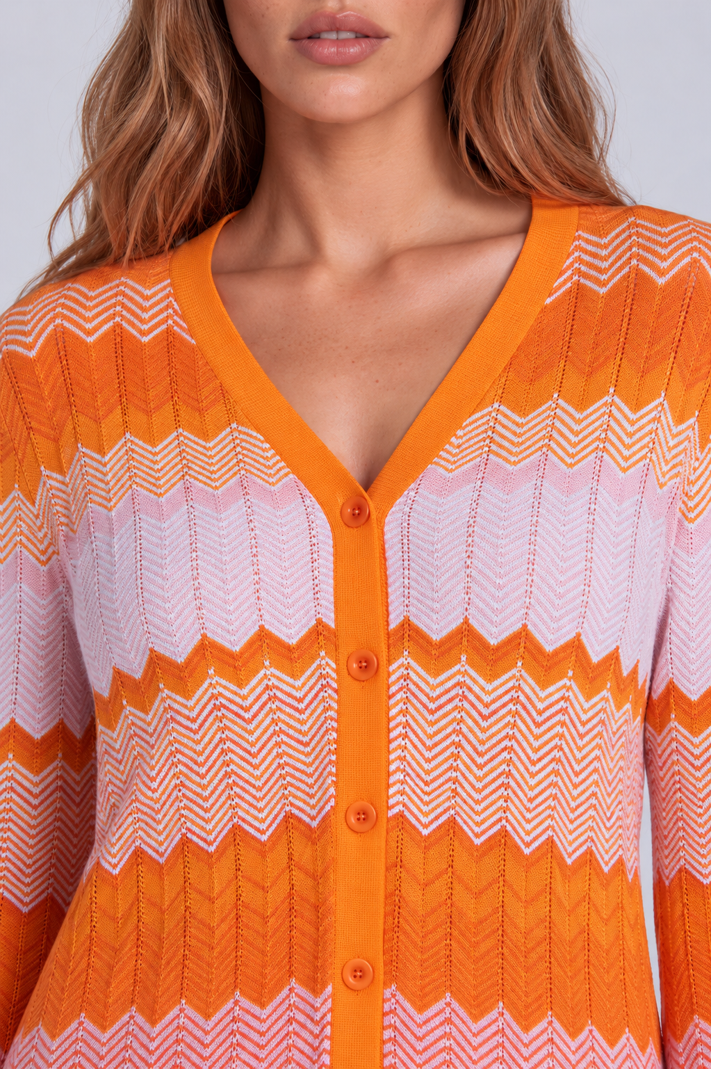 Front close-up of a model wearing the orange, pink, and white Tally Taylor Chevron Knit Dress & Pant Set - 51013, highlighting the V-neckline, button front, and textured chevron pattern