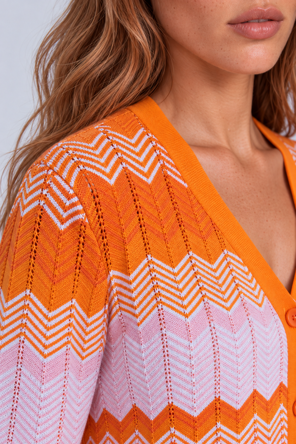 Shoulder close-up of a model wearing the Tally Taylor Chevron Knit Dress & Pant Set - 51013, showing the orange, pink, and white textured chevron knit design