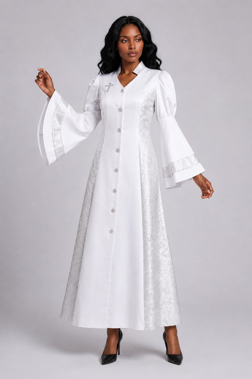 Front view of a model wearing the white and silver Tally Taylor Divine Elegance Rhinestone Robe - 4565 with patterned panels, bell sleeves, rhinestone buttons and a cross detail
