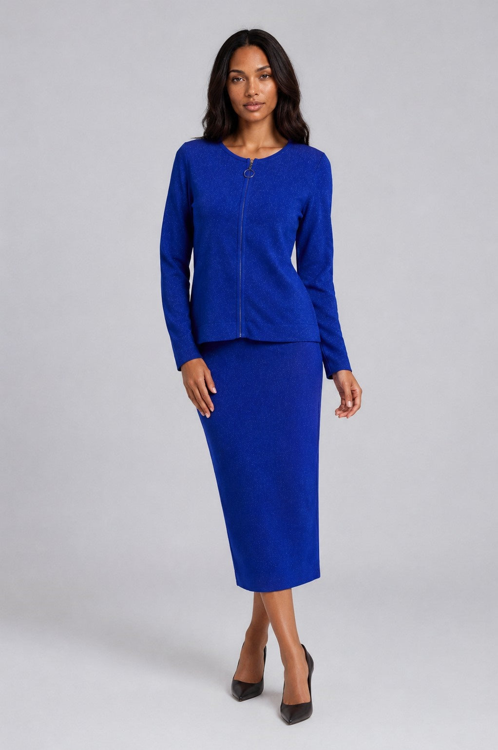 Front view of a model wearing the blue Tally Taylor Jeweled Detail Knit Skirt Suit - 5401 with a long-sleeve zip-front jacket, circular zipper pull, subtle shimmer, and matching midi skirt