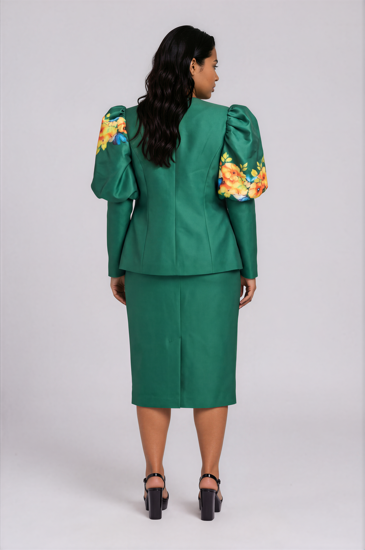 Back view of a plus-size model wearing the emerald green Tally Taylor Plus Size Floral Puff Sleeve Jacket & Midi Skirt Set – T5749W with floral puff sleeves and a skirt back slit