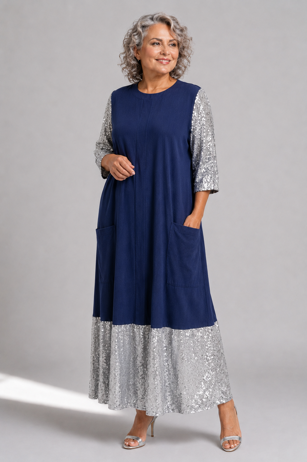 Plus size model wearing the Tally Taylor Sequin Sleeve Maxi Dress in navy and silver, featuring shimmering sequin sleeves and hem with front patch pockets, style S0272W.